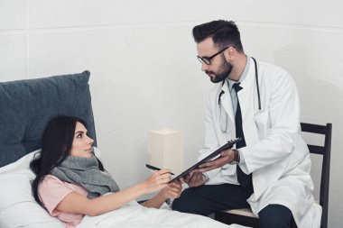 genç doktor hastaya imzalamak için Pano belgelerle vermek