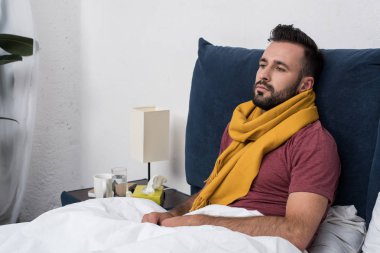 depressed sick young man lying in bed and looking away