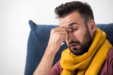 close-up portrait of sick young man with sinus infection touching his nose clipart