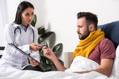 kadın doktor yatakta yatan hastaya Pano belgelerle vermek