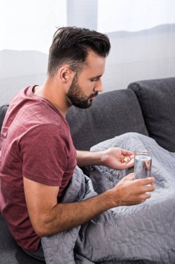 su ve hapları ile kanepede oturan hasta genç adam
