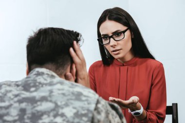 female psychiatrist talking to depressed soldier with ptsd during therapy session clipart