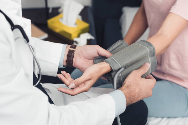 cropped shot of doctor measuring blood pressure of patient