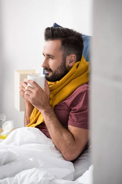 Sorrindo Jovem Doente Com Cachecol Segurando Xícara Chá Quente Enquanto — Fotografia de Stock