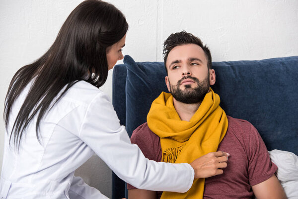 young female doctor using stethoscope to listen to patients breath while he lying in bed