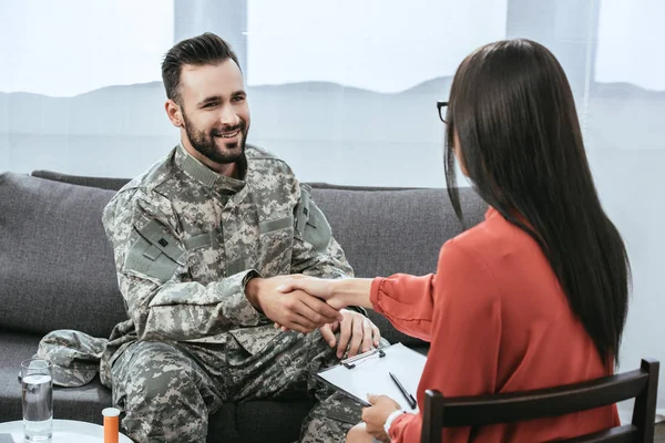Uśmiechnięty Żołnierz Drżenie Rąk Psychiatra Podczas Sesji Terapii — Zdjęcie stockowe