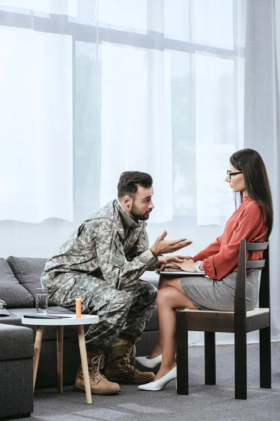mad soldier talking at psychiatrist and gesturing during therapy session