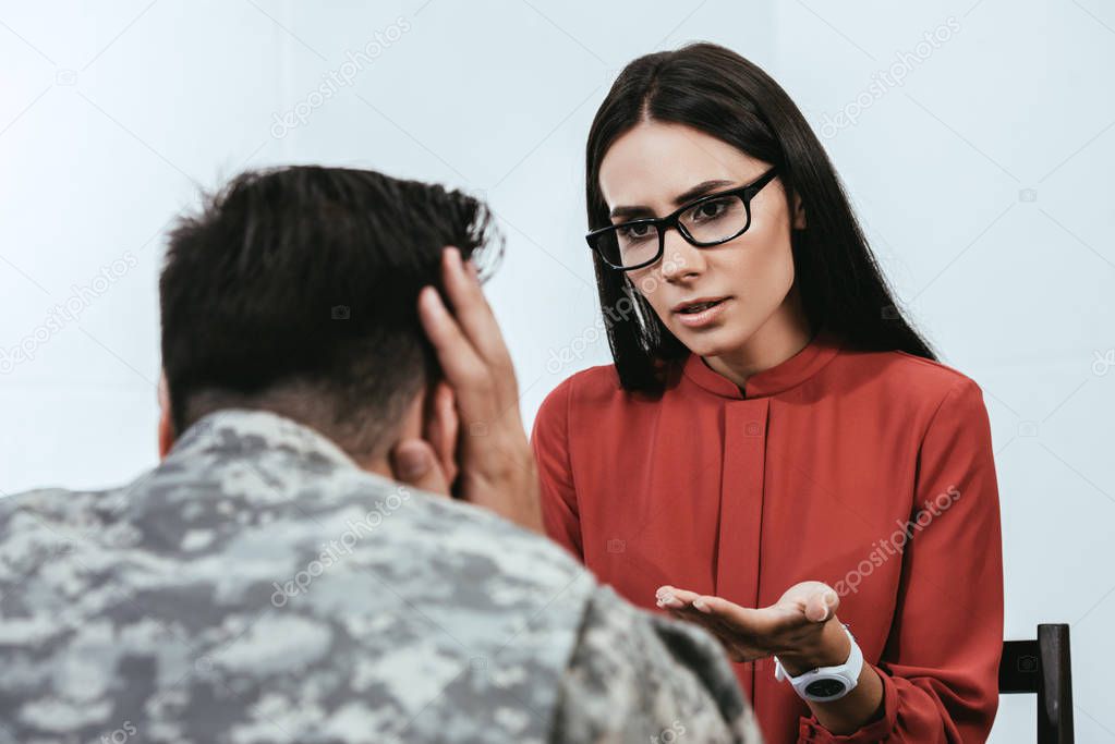 female psychiatrist talking to depressed soldier with ptsd during therapy session