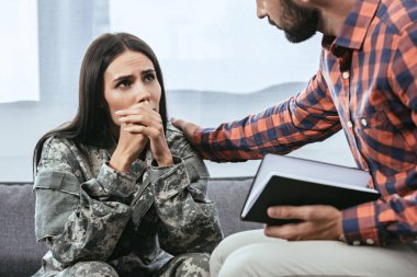 cropped shot of psychiatrist supporting crying female soldier during therapy session clipart