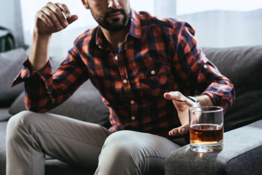 Genç adam kanepede otururken bardak viski alarak kırpılmış atış
