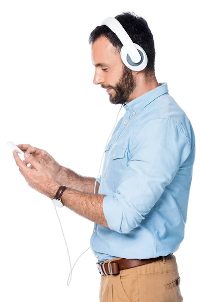 Vista Lateral Homem Barbudo Ouvindo Música Usando Smartphone Isolado Branco — Fotografia de Stock