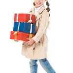 Adorable child in autumn coat holding gift boxes, isolated on white