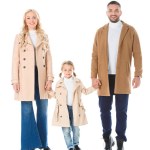 Happy parents holding hands with adorable daughter and posing in beige coats, isolated on white