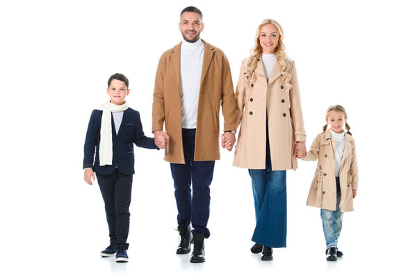 счастливые родители держатся за руки с детьми в осеннем наряде, изолированные на белом
