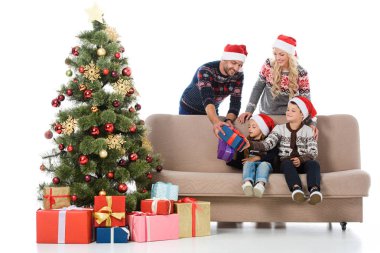 Noel ağacı, beyaz izole yakın oturan çocuklara hediye vermek Noel Baba şapkaları ebeveynler