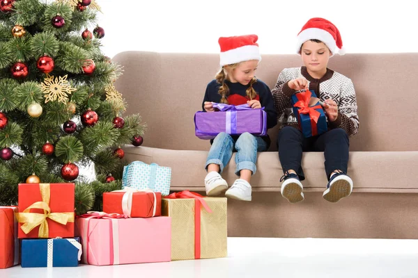 Broer Zus Kerstmuts Holding Presenteert Zittend Bank Buurt Van Kerstboom — Stockfoto