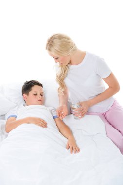 beyaz izole hasta oğlu için hap ve su veren anne