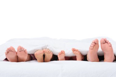 Aile ayak üzerinde beyaz izole beyaz battaniye altında yatakta