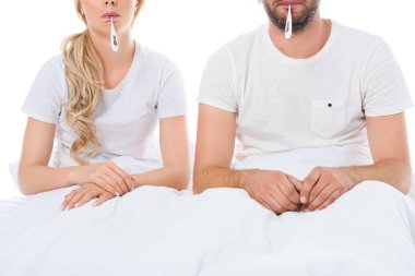 beyaz izole yatakta oturmuş elektronik termometre ile hasta çiftin kırpılmış görünümü
