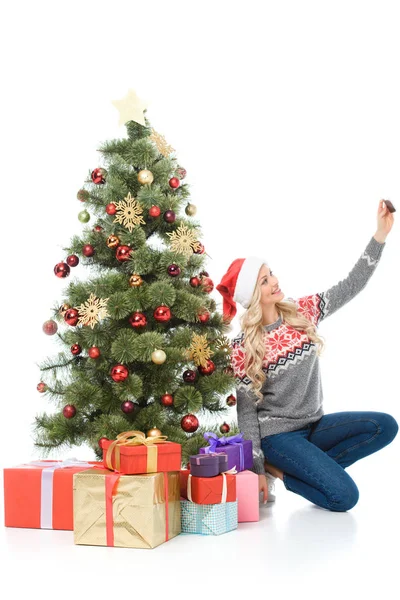Glückliche Frau Sitzt Neben Weihnachtsbaum Mit Geschenken Und Macht Selfie — kostenloses Stockfoto