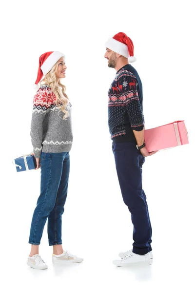 Christmas Couple Sweaters Santa Hats Hiding Gift Boxes Isolated White — Stock Photo, Image
