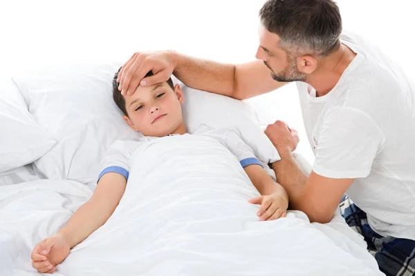 father touching forehead of sick son with temperature lying in bed, isolated on white