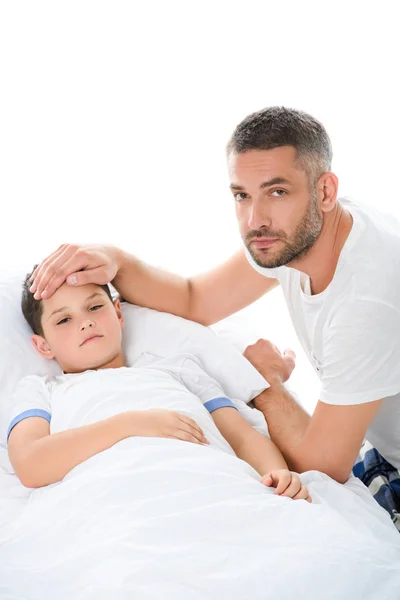 handsome father touching forehead of sick son with temperature, isolated on white