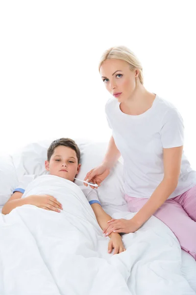 Madre Con Termometro Elettronico Seduta Vicino Figlio Malato Isolata Bianco — Foto stock gratuita