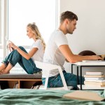 Vue latérale du jeune couple utilisant des appareils numériques à la maison