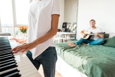 yatakta kız elektronik piyano evde oynarken süre akustik gitar çalmak adamın kısmi görünümü