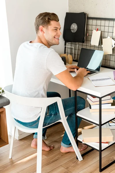 Młodzi Uśmiechnięty Człowiek Korzysta Laptopa Tabeli Home Office — Darmowe zdjęcie stockowe