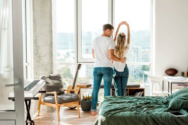 back view of young couple standing at window clipart