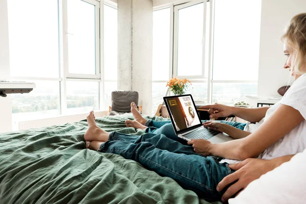 自宅のベッドで休んでいる間画面上にチケット オンライン レタリングとデジタルのラップトップを使用してカップルの部分的なビュー  — 無料ストックフォト