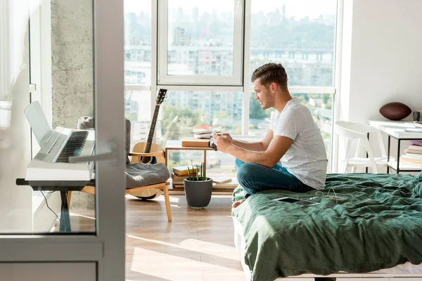 Vue Latérale Homme Utilisant Smartphone Tout Reposant Sur Lit Maison — Photo gratuite