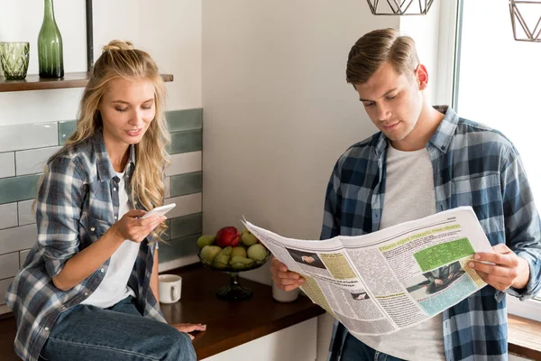 Casal Com Smartphone Jornal Passando Manhã Cozinha Casa — Fotografia de Stock