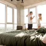 Mladý pár v pyžamu, táhnoucí se v okně doma ráno