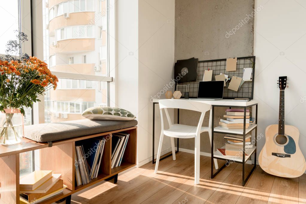 close up view of laptop with blank screen on table and acoustic guitar near by at home office