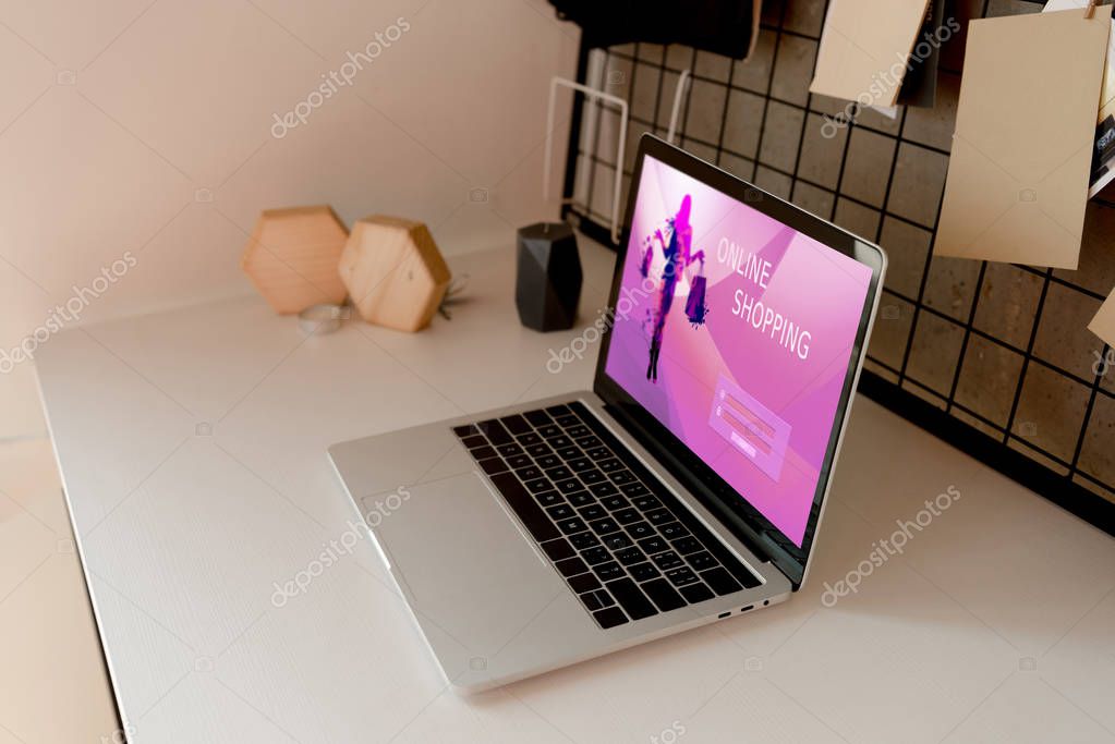Close up view of digital laptop with online shopping logo on screen on tabletop at home