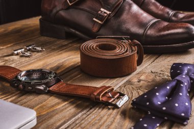 close up view of leather male accessories and shoes arranged on wooden tabletop clipart