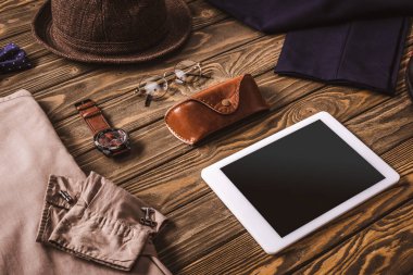 ahşap masa üzerinde erkek aksesuarları, şık giyim ve tablet görünümünü kapat