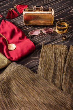 altın ve kırmızı moda kadınsı aksesuarları ve giyim ahşap yüzeyde oluşan görünümünü kapat