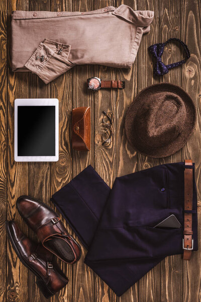 flat lay with stylish male clothing, hat, shoes and accessories arranged on wooden tabletop
