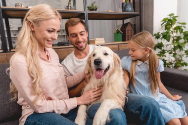 Anne ile kızı evde kanepede otururken köpekle oynamayı