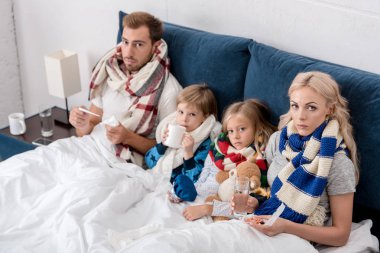 sick young family sitting in bed clipart