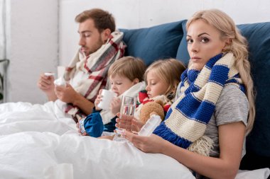 hastalıklı genç aile çeşitli tedavi yöntemleri ile birlikte yatakta oturuyor