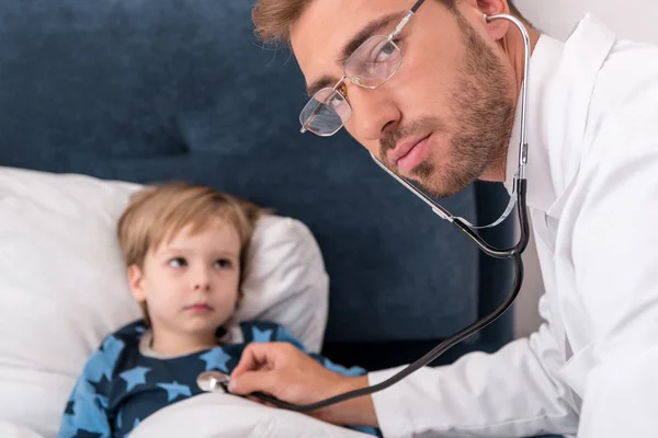 Pediatrician Litening Childs Breath Stethoscope Looking Camera While Lying Bed — Stock Photo, Image