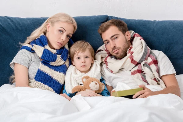 病気の両親と息子のベッドに座って カメラ目線 — ストック写真