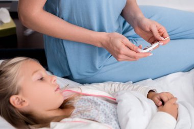 Kırpılan atış anne küçük kızları ısısı elektrik termometre ile kontrol