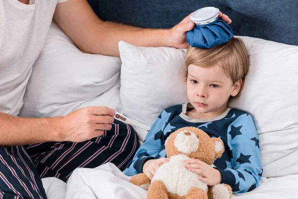 Bir Elektrik Termometre Ile Oğlu Sıcaklığını Kontrol Yatakta Kafasına Buz — Stok fotoğraf