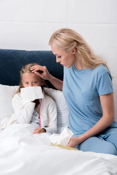 Junge Mutter Kümmert Sich Ihre Tochter Während Sie Nase Pustet — kostenloses Stockfoto